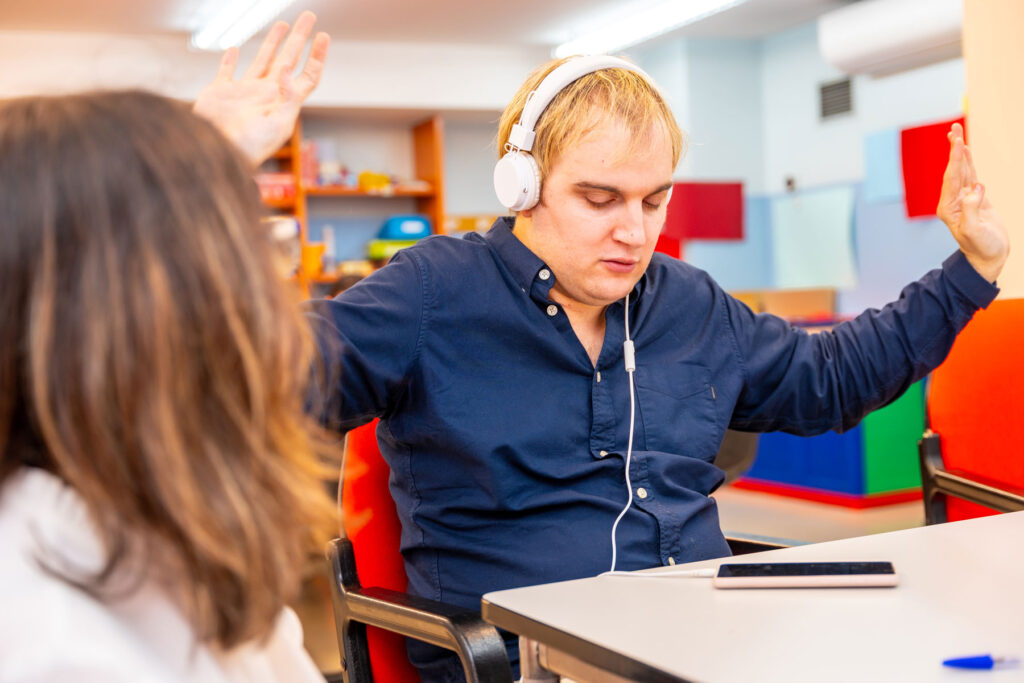 Accompagnement d’un adulte avec autisme lors d’une activité structurée favorisant la régulation sensorielle et l’autonomie, dans un environnement éducatif sécurisé et adapté.